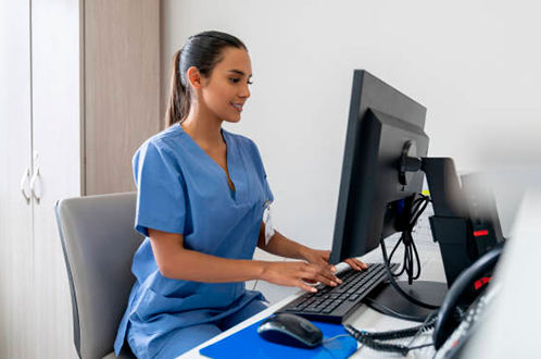 Gesundheits- und Krankenpflegerin dokumentiert am Computer.