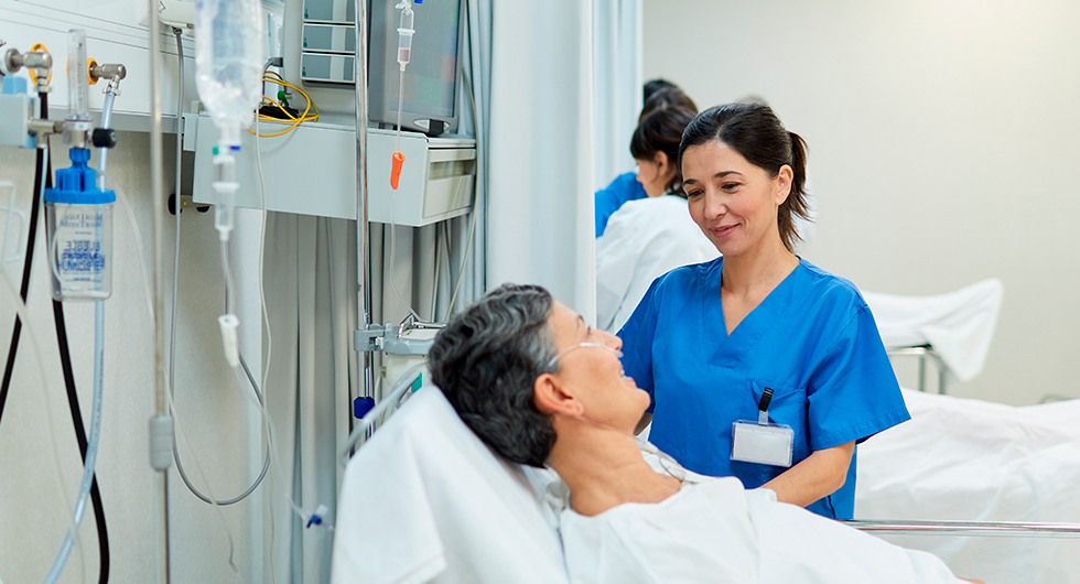 Kardiologische Fachkrankenschwester bei der Behandlung am Bett einer Patientin.